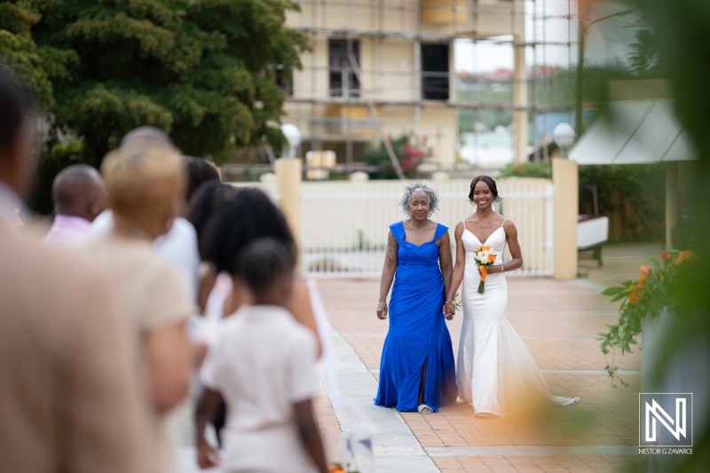 Beautiful bride walks down the aisle with her mother during a destination wedding at Avila Beach Hotel in Curacao