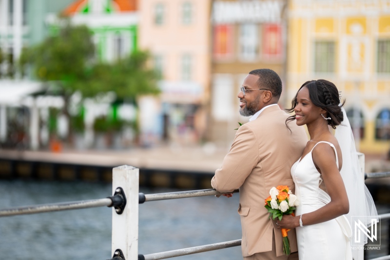 Couple celebrates love during their destination wedding at Avila Beach Hotel in Curacao with colorful buildings in the background