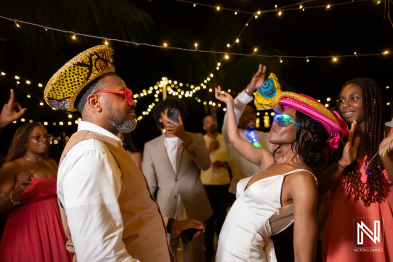 Celebration of love at a destination wedding in Avila Beach Hotel, Curacao with lively guests and fun hats