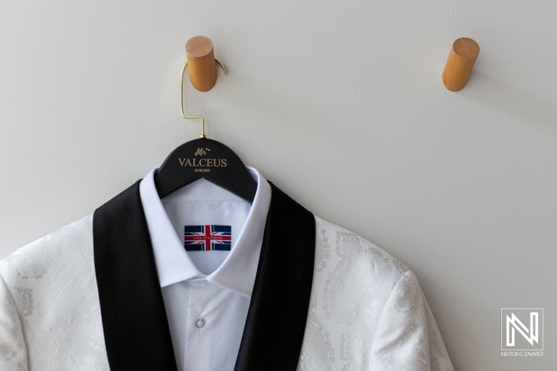 Elegant Tuxedo Displayed on a Hanger in a Stylish Setting, Showcasing Attention to Detail With British Flag Emblem on the Collar and Classic Black Lapel, Perfect for a Formal Event