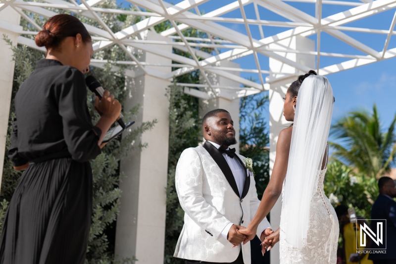 A Couple Exchanging Vows in a Beautiful Outdoor Ceremony Under a Bright Blue Sky Surrounded by Greenery at a Tropical Wedding Venue