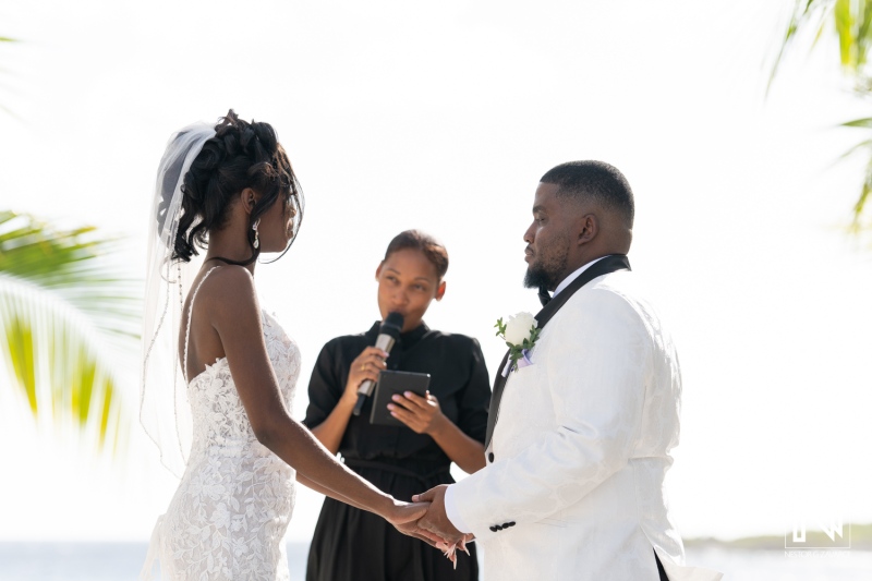 Couple Exchanging Vows During a Beach Wedding Ceremony at Sunset With a Serene Ocean Backdrop and an Officiant Present for the Special Moment