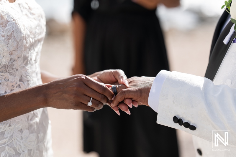 A Couple Exchanges Wedding Rings During a Beach Ceremony at Sunset, Surrounded by Loved Ones While Capturing a Moment of Love and Commitment