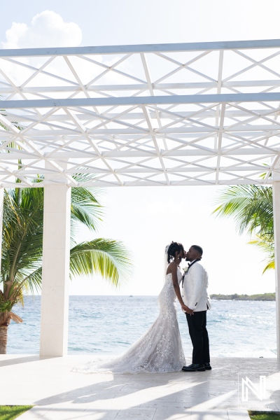 A Beautiful Couple Shares a Tender Kiss Under a Modern Canopy by the Ocean During Their Wedding Ceremony in a Tropical Paradise