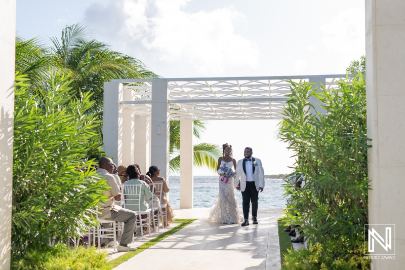 A Bride and Groom Walk Down the Aisle in an Outdoor Wedding Ceremony by the Ocean Under a Clear Sky During the Afternoon