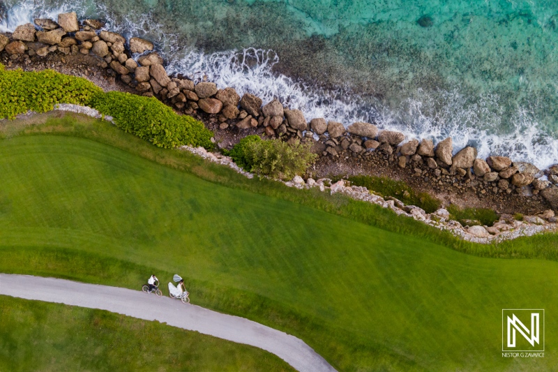 Scenic Coastal Pathway Featuring Two Cyclists Enjoying a Peaceful Ride Along the Shore on a Sunny Day With Clear Turquoise Waters and Lush Greenery in the Background