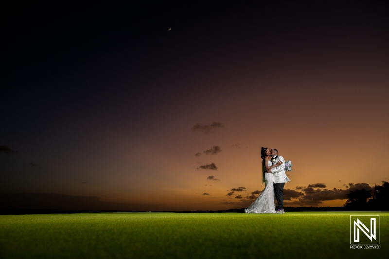 A Couple Embraces at Sunset on a Lush Green Lawn, Celebrating Their Union in a Picturesque Outdoor Setting With a Vibrant Sky