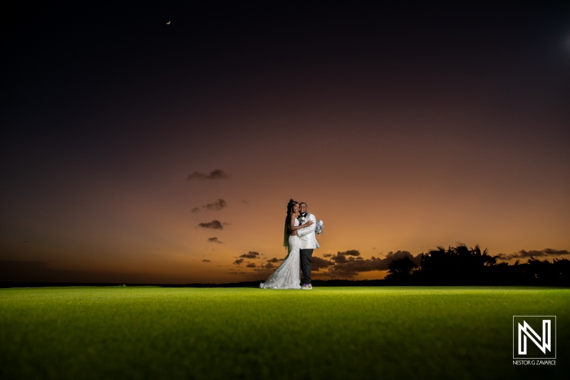 A Couple Embraces Under a Colorful Sunset on a Lush Green Lawn at an Outdoor Wedding Ceremony, Capturing a Romantic Moment in a Serene Setting