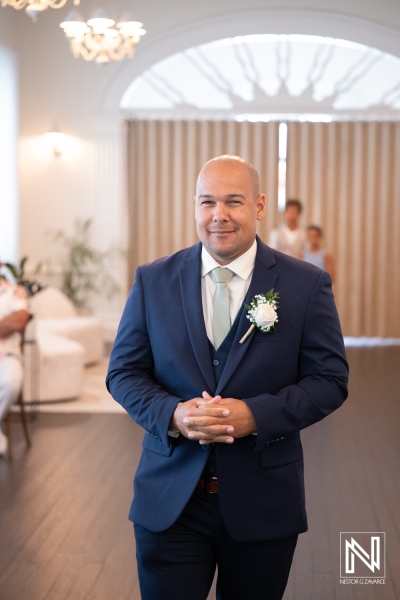Groom smiles while walking down the aisle at a wedding ceremony in Kranshi, Curacao on a sunny day