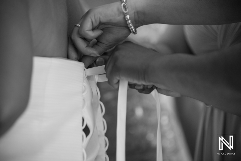 Bridesmaid  hands hepling the bride to dress