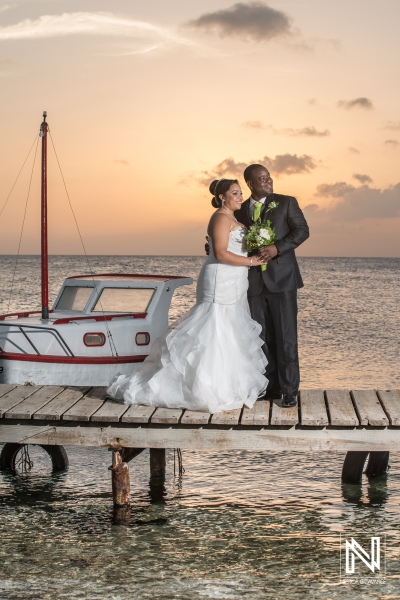 Bride and groom posing on the beach pier with a Curacao fisherman boat in the sunset
