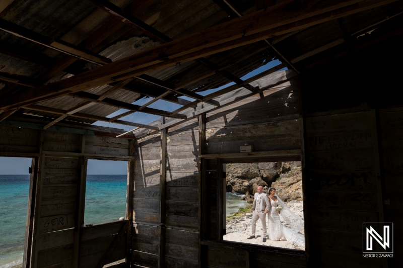 Couple celebrates wedding at Playa Hunku in Curacao with beach view and rustic backdrop