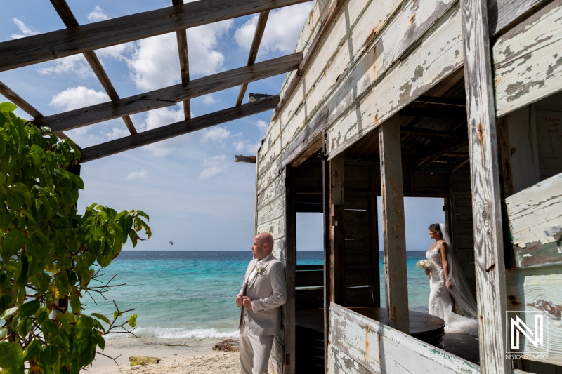 Wedding ceremony at Playa Hunku in Curacao presents a couple by the beach with an old building structure