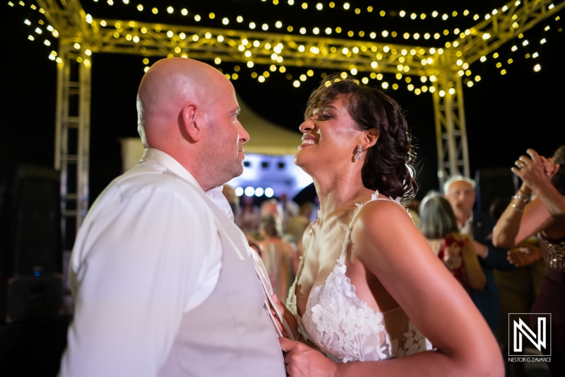 Couple shares a dance together during their wedding at Playa Hunku in Curacao at night beneath string lights