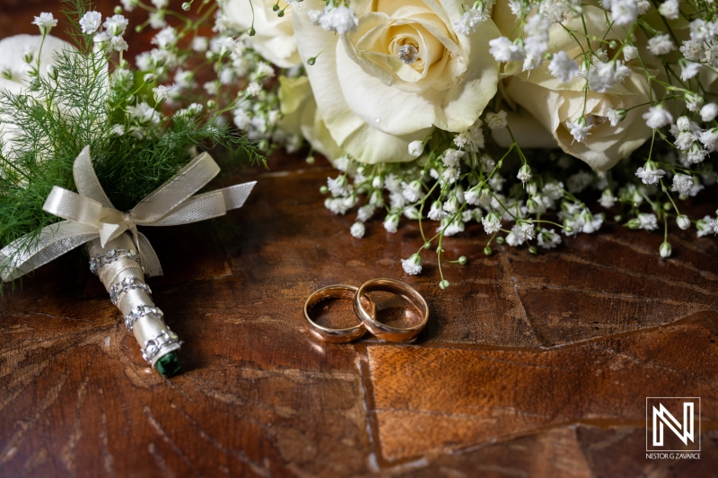 White rose groom boutonniere, wedding rings and bride bouquet