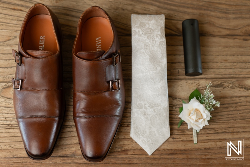 Elegant wedding attire details showcasing brown shoes, a tie, and a boutonniere at Landhuis Klein Santa Martha in Curacao for a romantic celebration