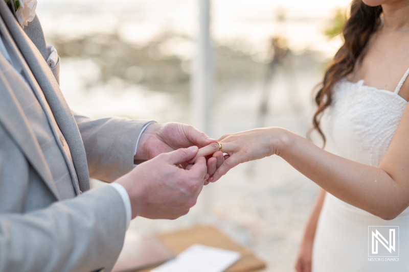 Couple exchanges wedding rings during ceremony at Landhuis San Nicolas in Curacao on a picturesque day