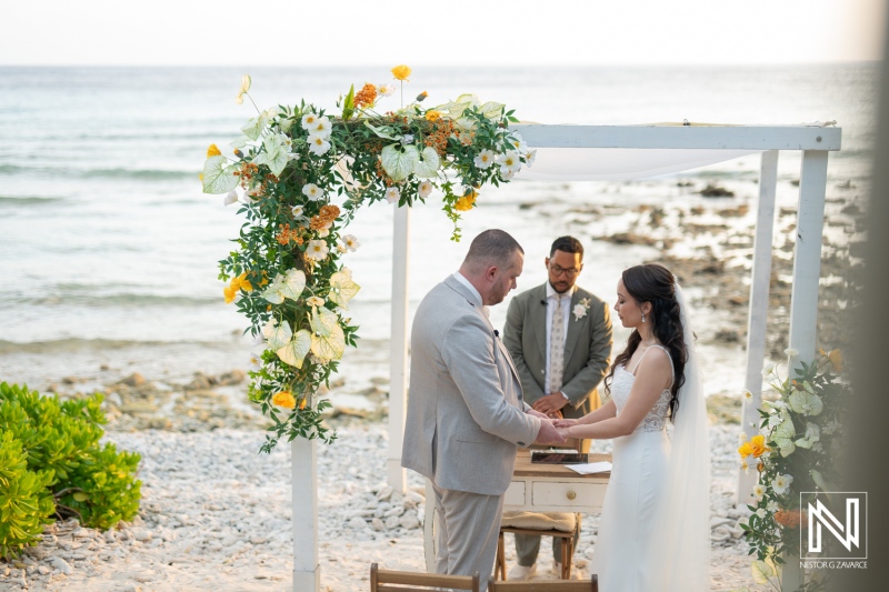 Beautiful wedding ceremony at Landhuis San Nicolas in Curacao with a stunning beach backdrop as the couple exchanges vows