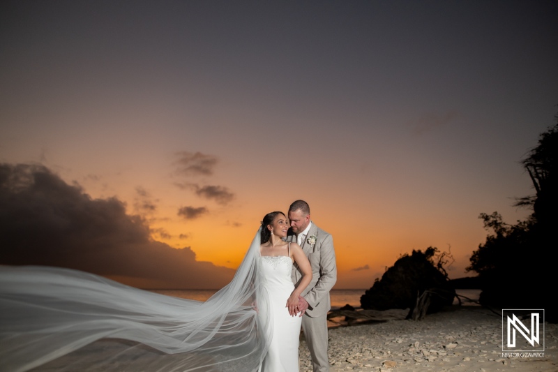 Couple exchanges vows during a romantic wedding ceremony at Landhuis San Nicolas, Curacao, under a stunning sunset sky