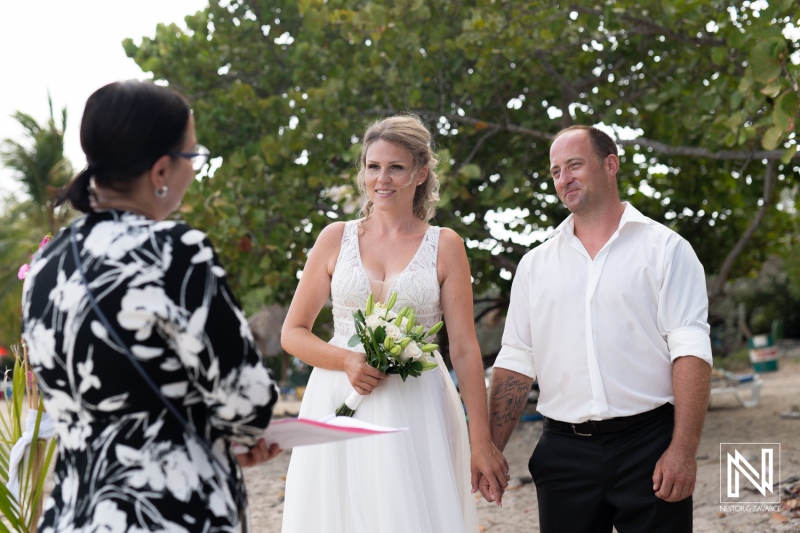 A joyful beach wedding ceremony takes place at sunset, featuring a bride and groom exchanging vows amidst tropical greenery and soft sand