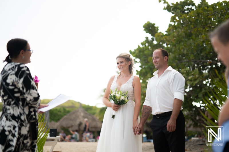 A joyful beach wedding ceremony taking place with a couple holding hands, surrounded by nature and family in a tropical setting during the afternoon