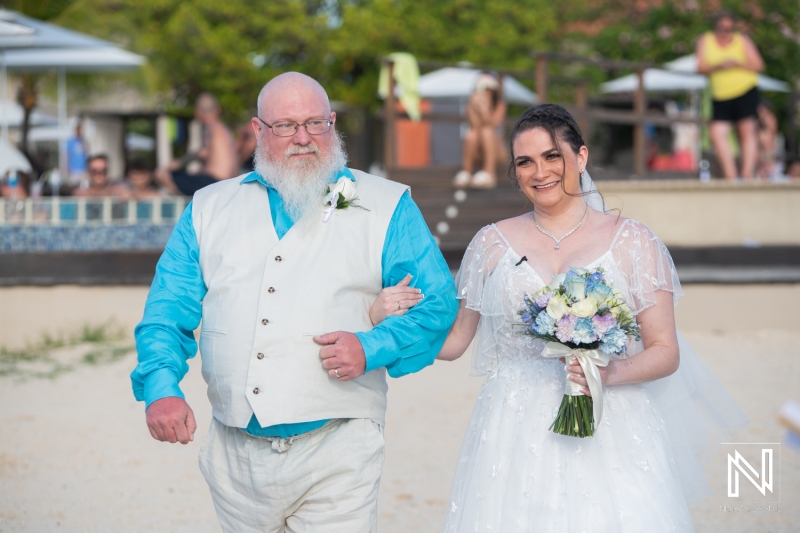 Bride and father walking down the isle at the beach
