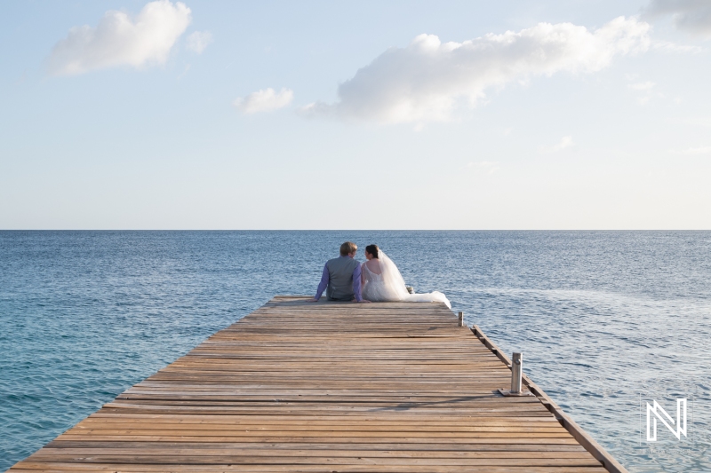 Bride and groom at the pier looking at the sea