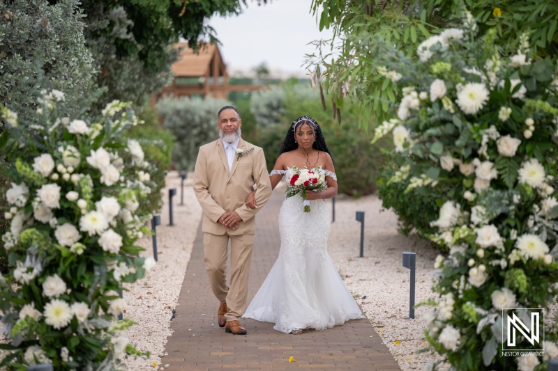 Couple walks together at their wedding in Dreams Curacao Resort surrounded by flowers and greenery