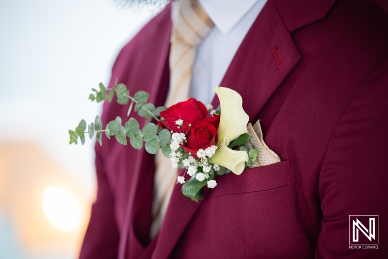 Groom's attire with red roses and calalilies at a wedding in Dreams Curacao Resort