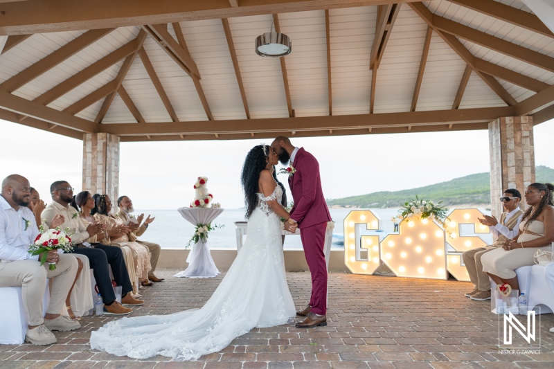 Couple exchanges vows during a wedding ceremony at Dreams Curacao Resort with guests in attendance near the beach
