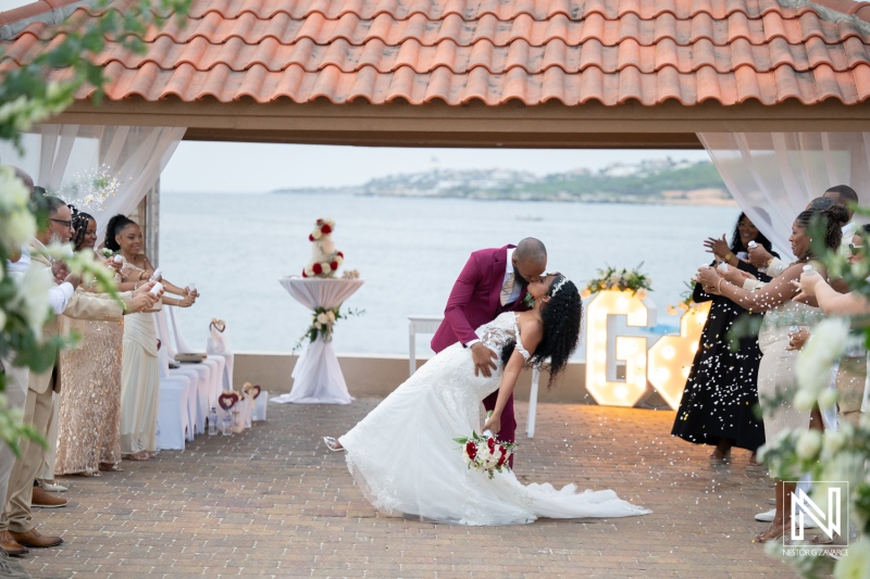 Couple shares a kiss during wedding ceremony at Dreams Curacao Resort near the ocean in a joyful celebration with guests