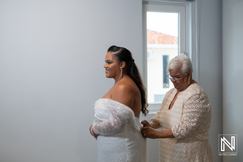 Bride prepares for wedding ceremony in Curacao with mother assisting in elegant setting