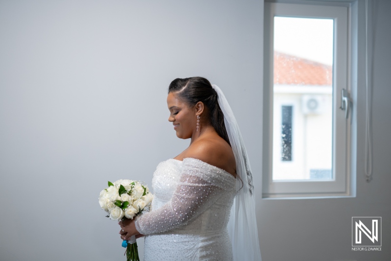 Wedding celebration in Curacao with a bride holding a bouquet of white roses in a bright room with natural light capturing the joyful moment