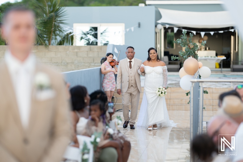 Elegant wedding ceremony in Curacao with a bride walking down the aisle accompanied by her father and beautiful floral decorations