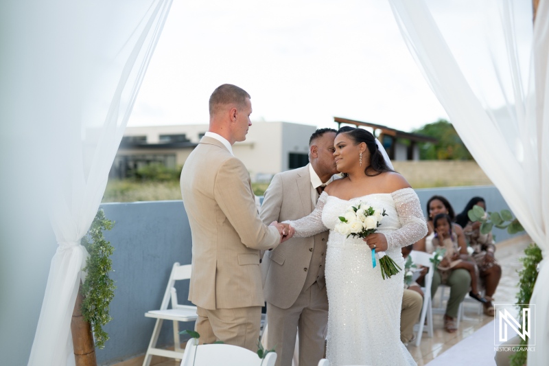 Couple exchanging vows in a scenic wedding ceremony in Curacao on a beautiful sunny day surrounded by friends and family