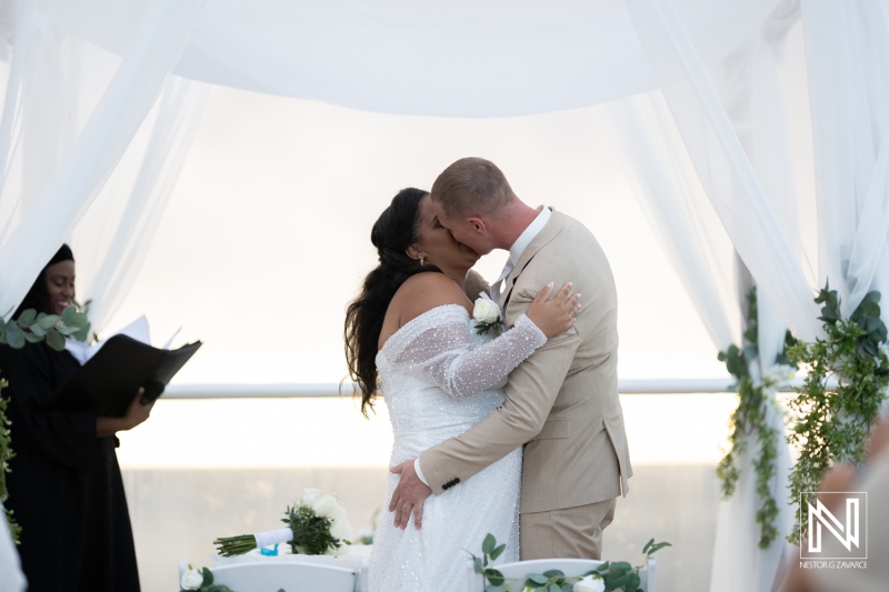 Wedding ceremony in Curacao celebrates love with an intimate kiss between the newlyweds under a floral drape