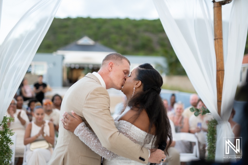 Couple shares a romantic kiss during their wedding ceremony in Curacao with guests in attendance