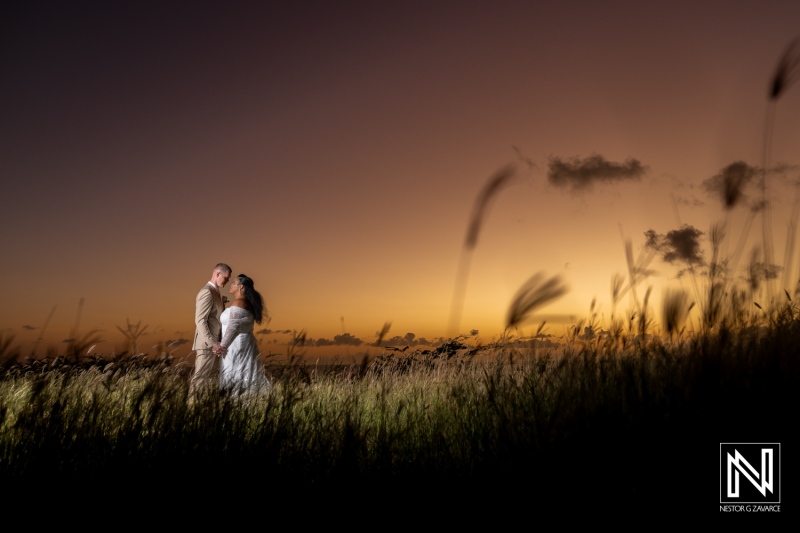 Romantic wedding couple embracing against a stunning Curacao sunset backdrop with vibrant colors blending in the sky