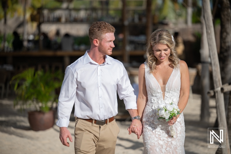 Couple walks together during wedding ceremony at Mood Beach in Curacao under bright sunlight