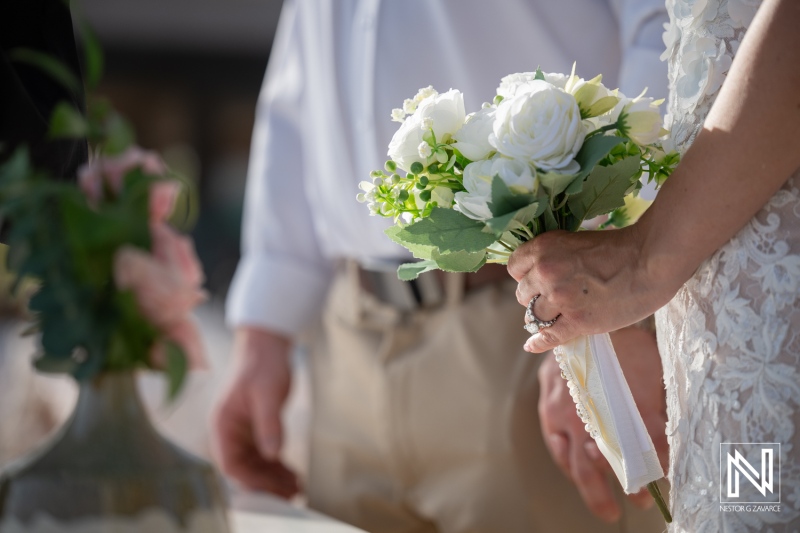 Wedding ceremony taking place at Mood Beach in Curacao with the bride holding a bouquet and the groom nearby
