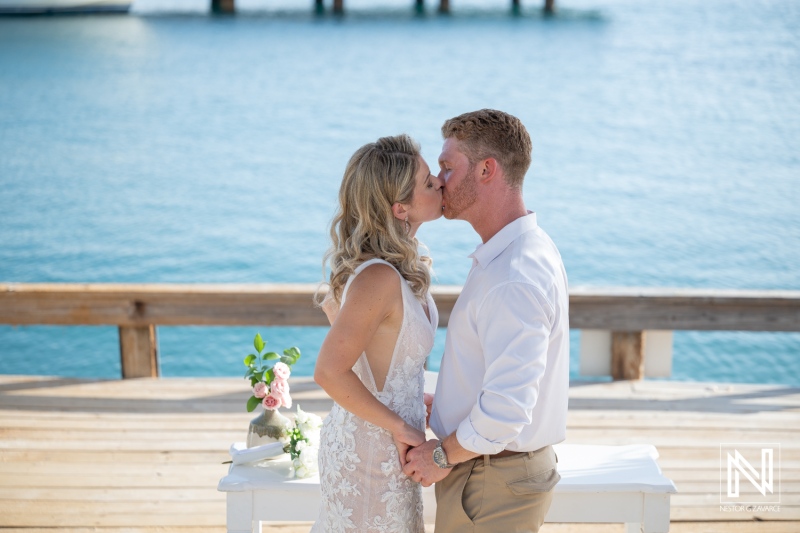 Wedding ceremony at Mood Beach in Curacao with couple holding hands and sharing kiss near the water