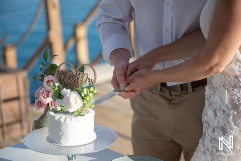 Couple cutting wedding cake at Mood Beach in Curacao during sunset celebration