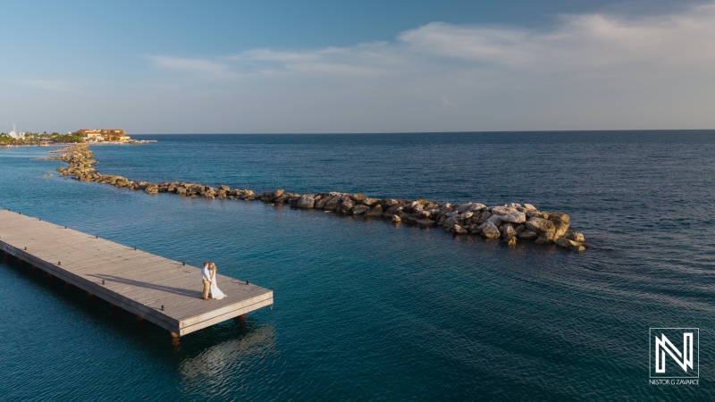 Couple celebrates their wedding on the dock at Mood Beach in Curacao during sunset with the ocean in the background