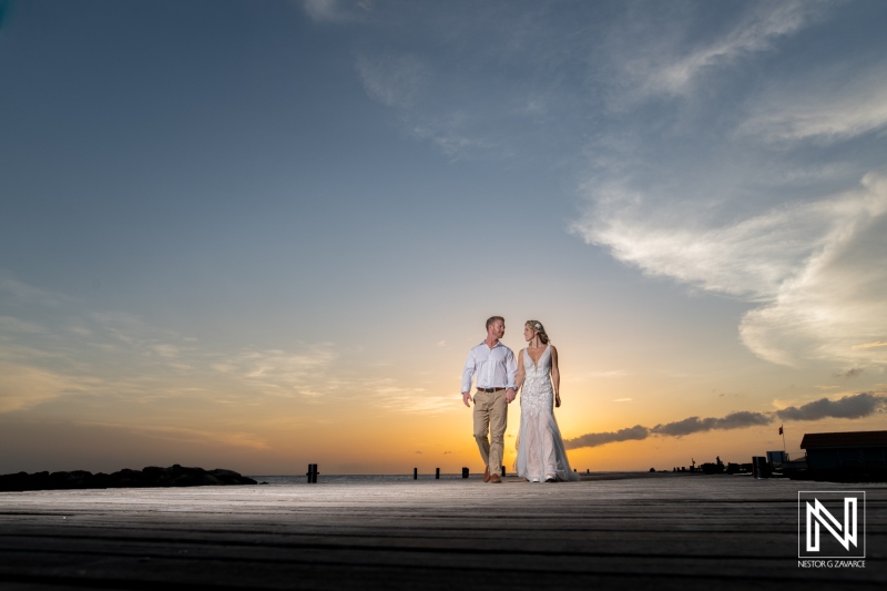 Couple walks together on the beach at sunset during a wedding ceremony in Curacao