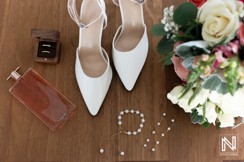 Elegant Bridal Accessories Laid out on Wooden Surface With White Shoes, Bouquet, Perfume, and Jewelry Arranged Neatly, Capturing Pre-Wedding Moments During Daytime