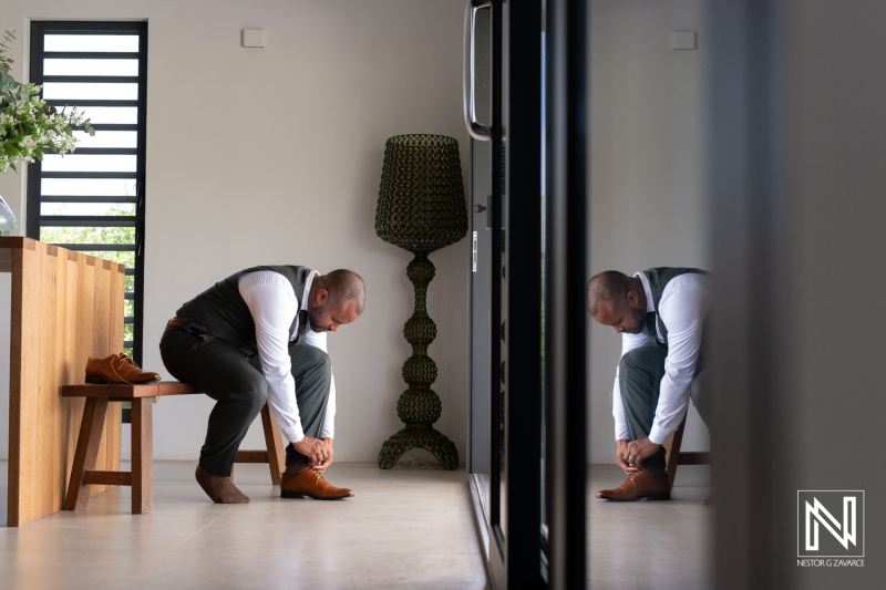 A Man Getting Ready by Putting on Brown Dress Shoes in a Modern Home Interior With a Stylish Lamp and Wooden Furniture in the Background During Daylight