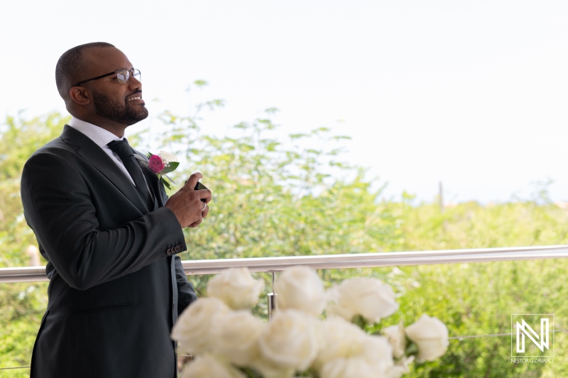 A Man in a Suit Stands Outdoors, Speaking With Confidence and Emotion During a Meaningful Event Surrounded by Greenery and White Roses