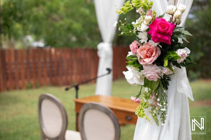 A Beautiful Floral Arrangement Featuring Roses and Greenery Decorates an Outdoor Wedding Ceremony Setting in a Serene Garden During Daylight