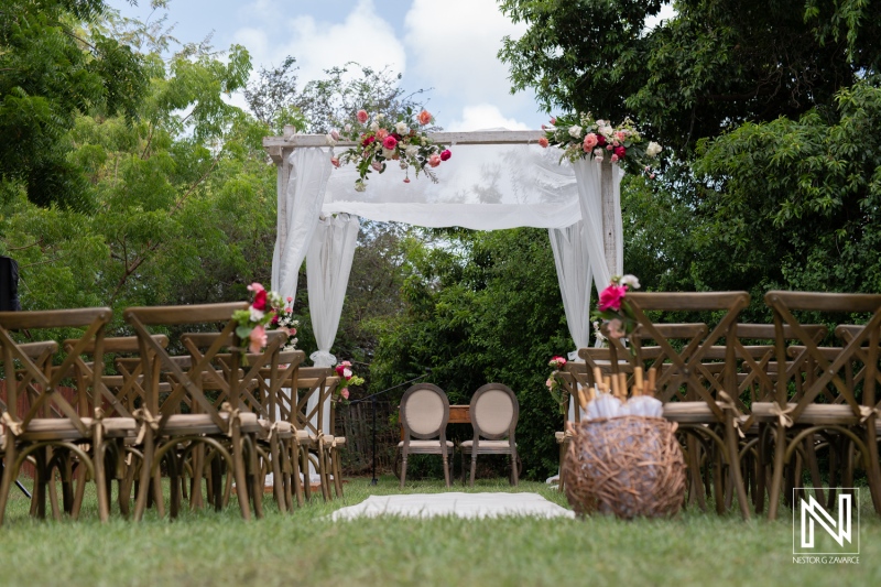 A Beautiful Outdoor Wedding Ceremony Set up With Floral Decor, Wooden Chairs, and an Elegant Arch in a Lush Green Garden on a Sunny Day