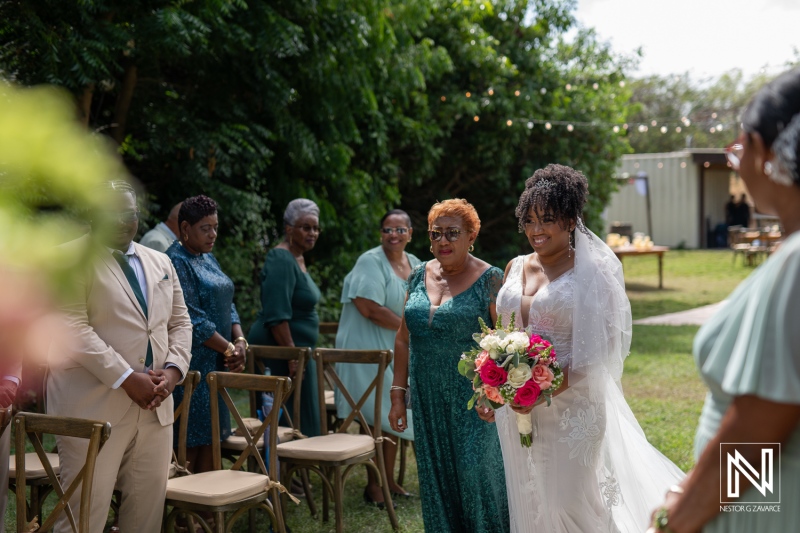 A Joyful Bride Walks Down the Aisle Surrounded by Family and Friends at a Picturesque Outdoor Wedding Ceremony in a Lush Garden Setting During a Sunny Afternoon